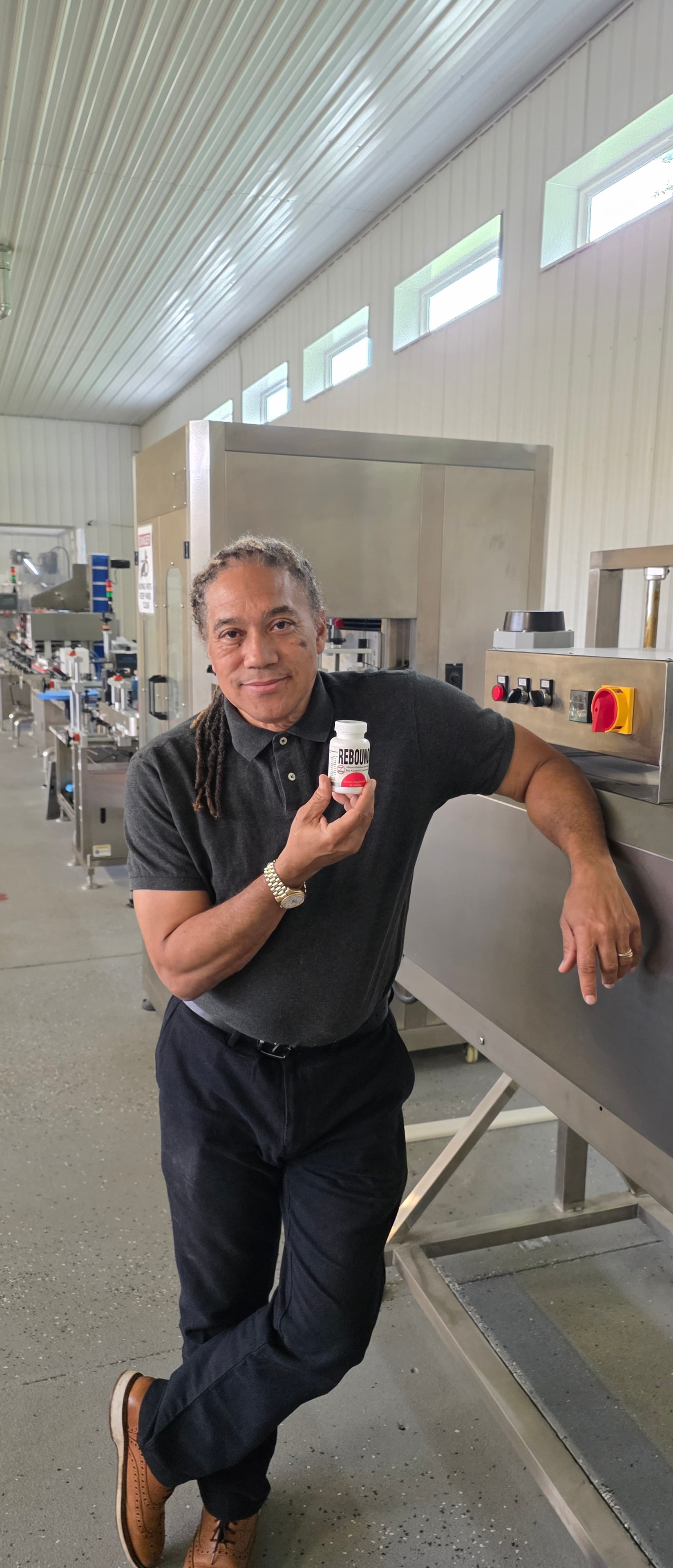 Wallace Peoples holding a bottle of Rebound Vitamins at the production line